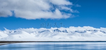 蓝天白云下平静湖泊与壮丽雪山